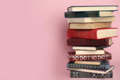 Photo of Stack of hardcover books on pink background. Space for text