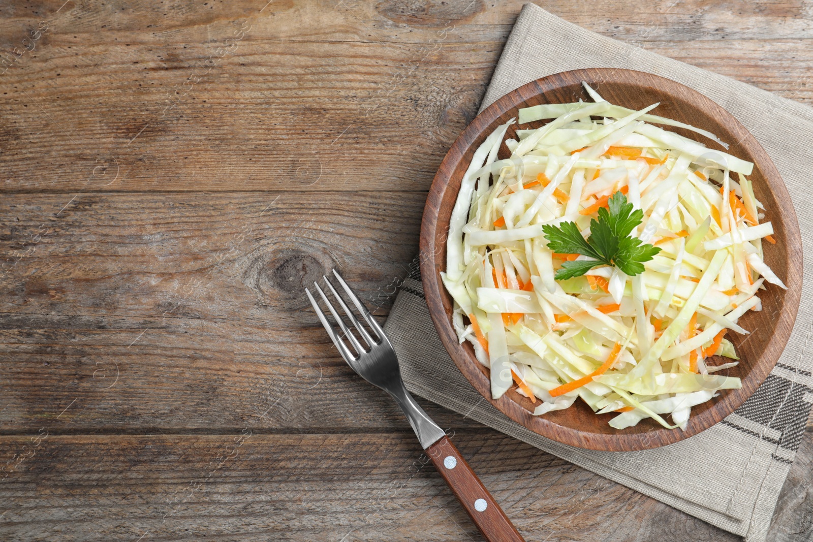 Photo of Fresh cabbage salad served on wooden table, flat lay. Space for text