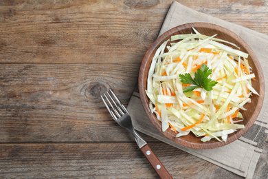 Photo of Fresh cabbage salad served on wooden table, flat lay. Space for text