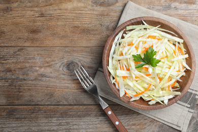 Fresh cabbage salad served on wooden table, flat lay. Space for text