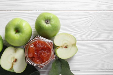 Photo of Glass jar of delicious apple jam and fresh fruits on white wooden table, flat lay. Space for text