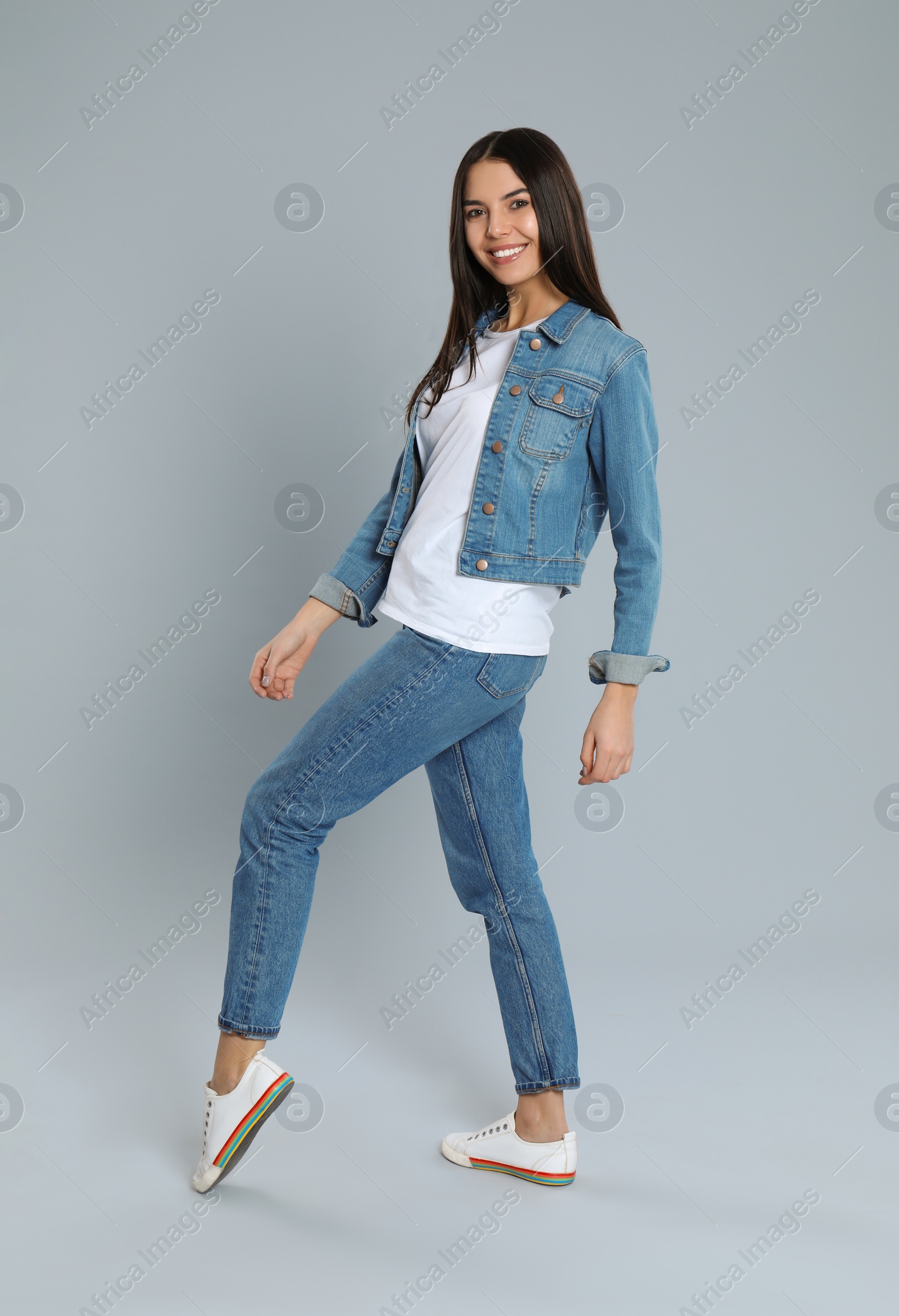 Photo of Young woman in stylish jeans on grey background