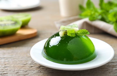 Photo of Delicious fresh green jelly with kiwi slices and mint on wooden table