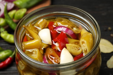 Photo of Glass jar with pickled peppers on table, closeup