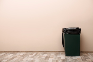 Photo of Trash bin near color wall indoors, space for text. Waste recycling