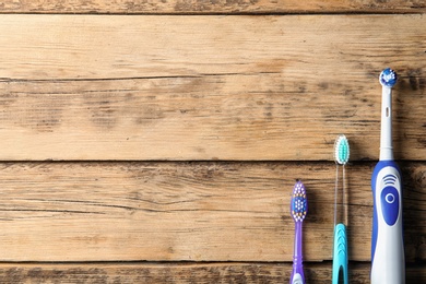 Flat lay composition with electric and manual toothbrushes on wooden background