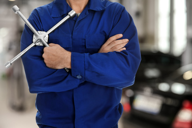 Image of Professional mechanic with lug wrench at tire shop, closeup