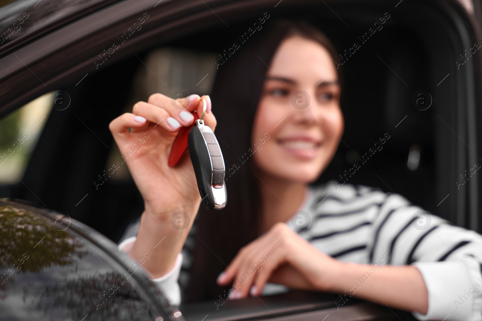 Photo of Woman holding car flip key inside her vehicle, selective focus