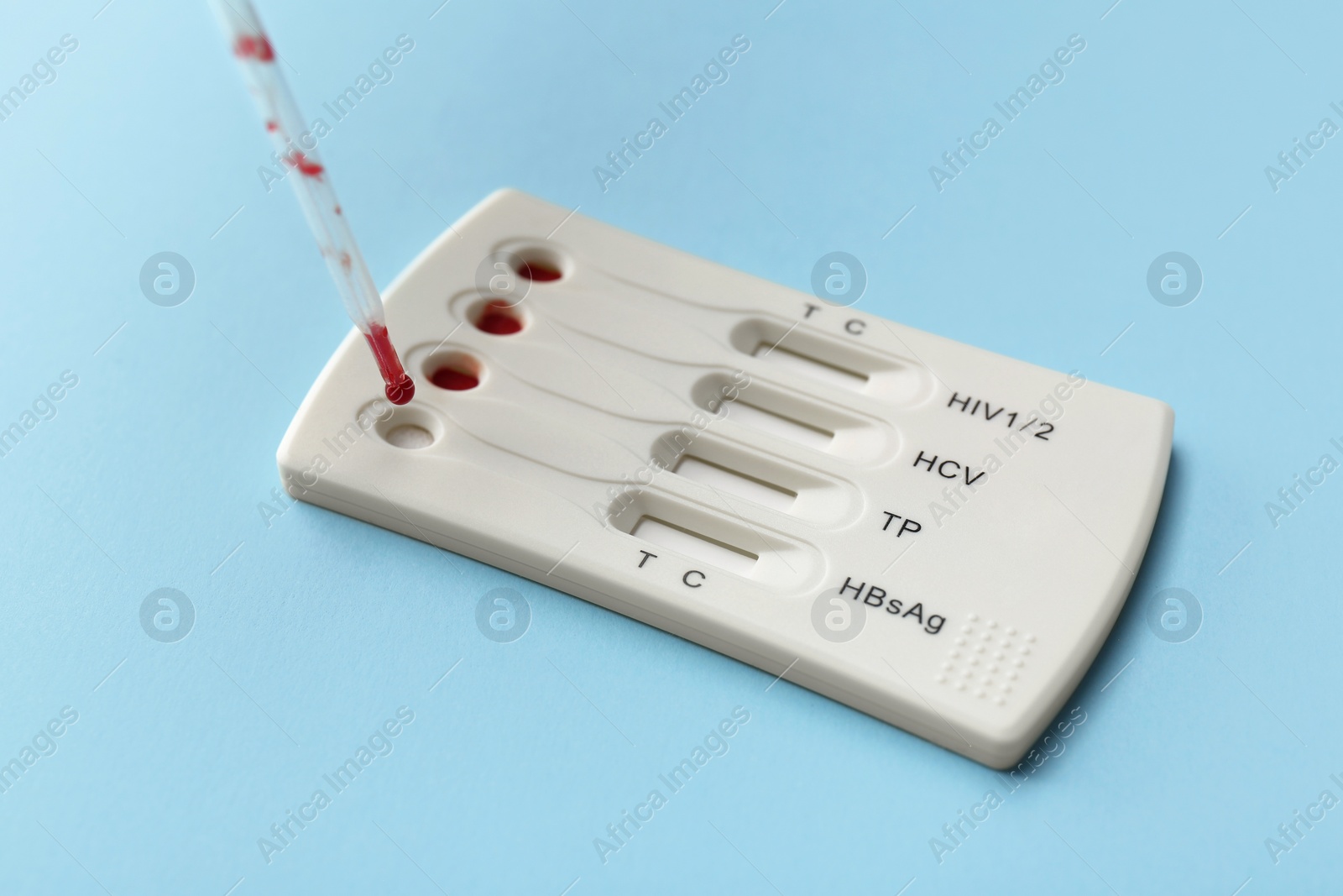 Photo of Dropping blood sample onto disposable multi-infection express test cassette with pipette on light blue background