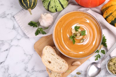 Photo of Delicious pumpkin soup served on white marble table, flat lay. Space for text