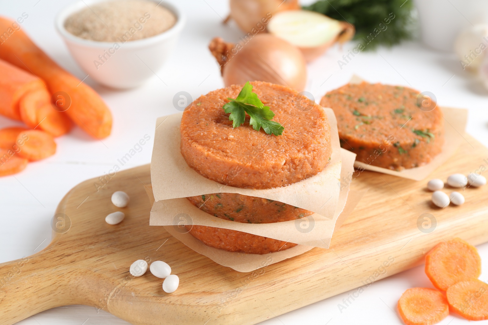 Uncooked carrot cutlets and ingredients on white wooden table. Vegetarian product Photo of Uncooked carrot cutlets and ingredients on white wooden table. Vegetarian product