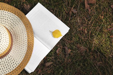 Photo of Open book, hat and leaf on grass outdoors, flat lay. Space for text
