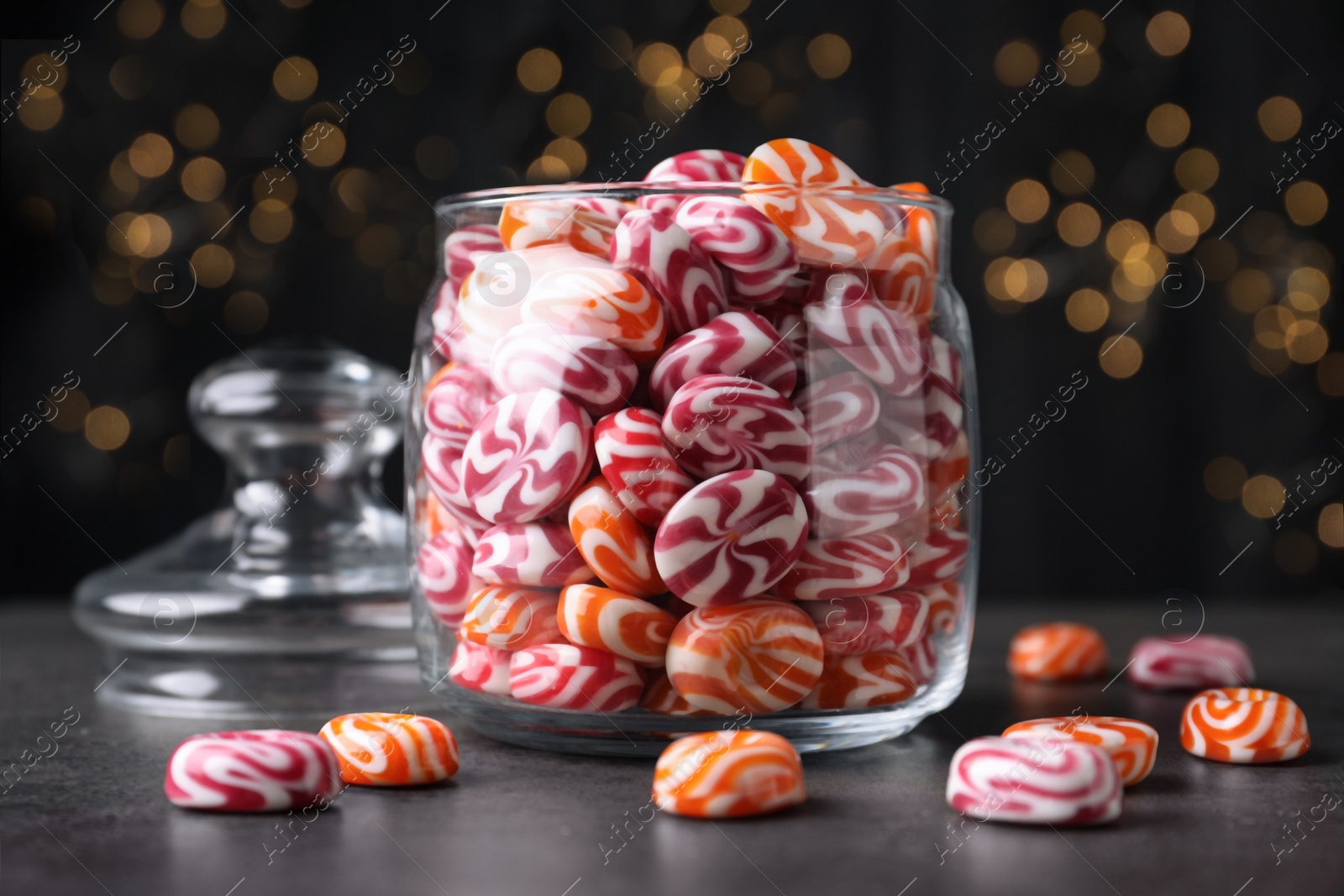 Photo of Glass jar with colorful hard candies on dark table