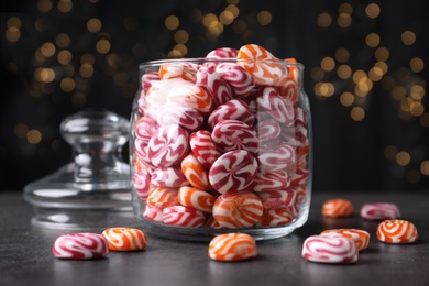 Photo of Glass jar with colorful hard candies on dark table
