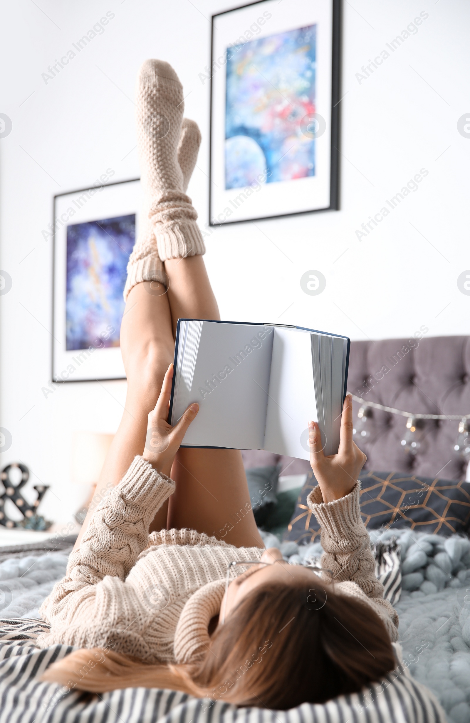 Photo of Young woman reading book on bed at home