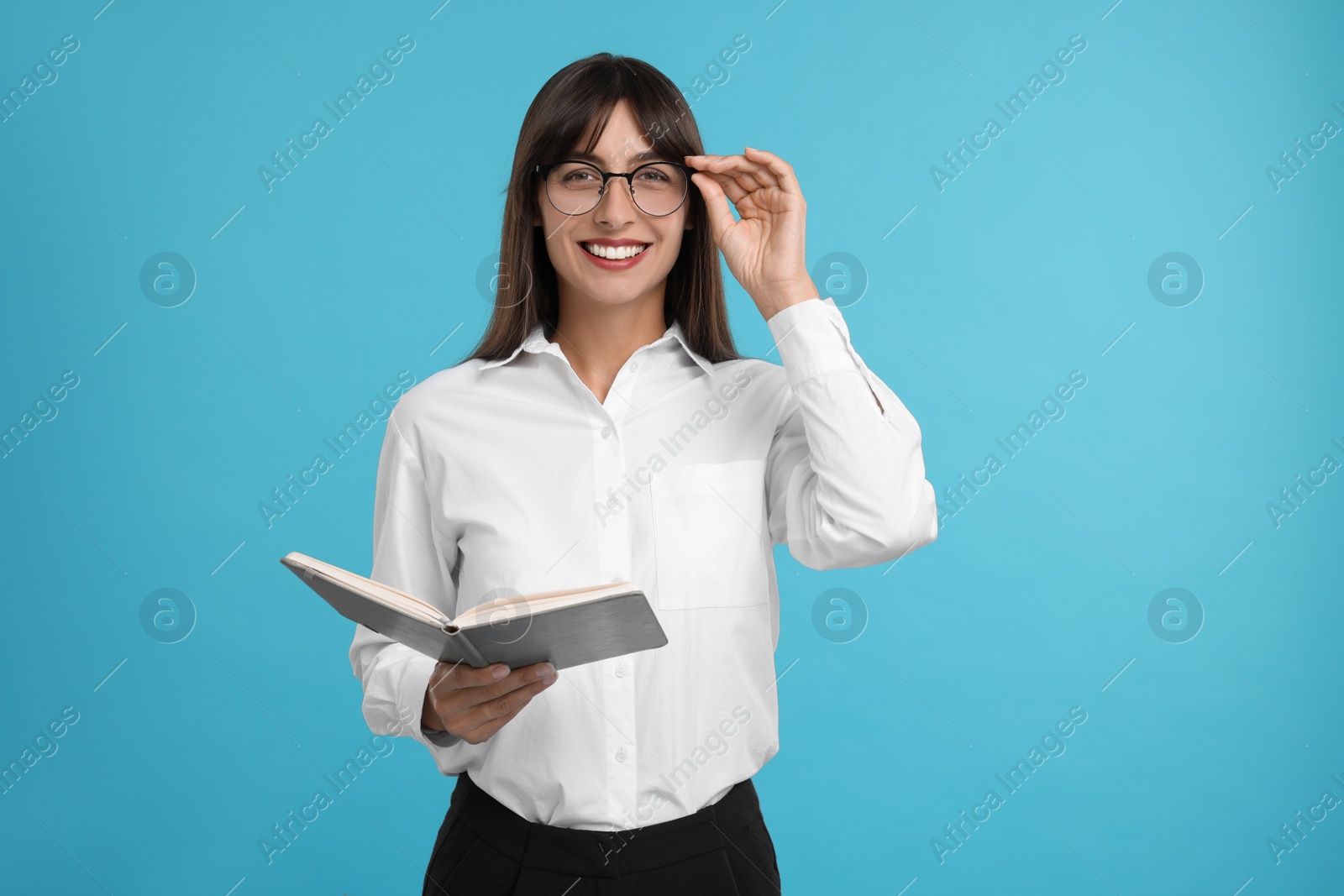 Photo of Happy secretary with notebook on light blue background