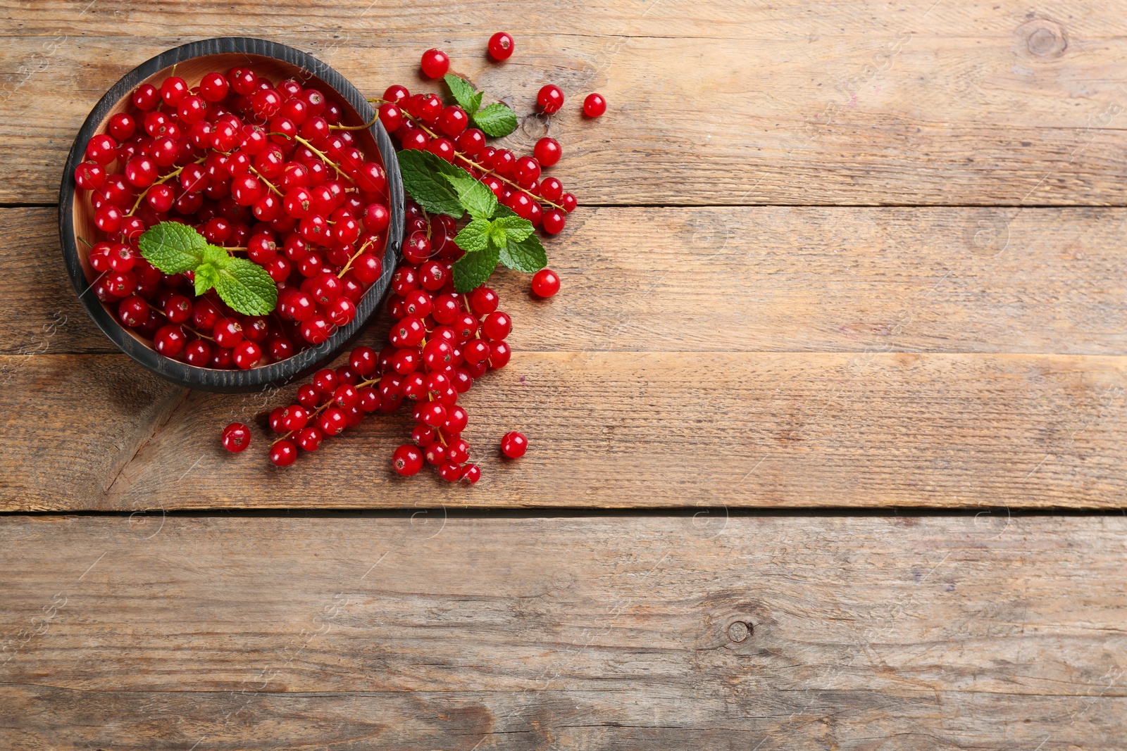 Photo of Delicious red currants and mint on wooden table, flat lay. Space for text