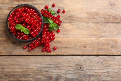 Photo of Delicious red currants and mint on wooden table, flat lay. Space for text