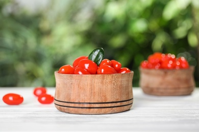 Photo of Bowl with fresh goji berries on white wooden table against blurred background. Space for text