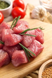 Photo of Cooking delicious goulash. Raw beef meat with rosemary on wooden board, closeup