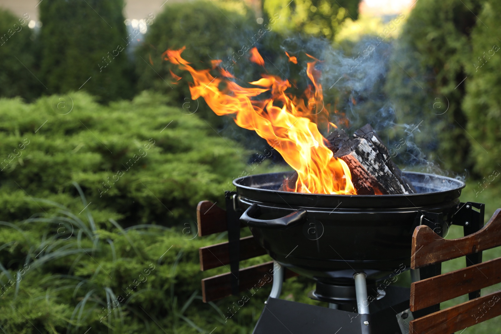 Photo of Portable barbecue grill with fire flames outdoors. Space for text