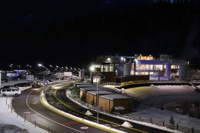 Photo of Lit road with snow on sides leading to ski resort in evening