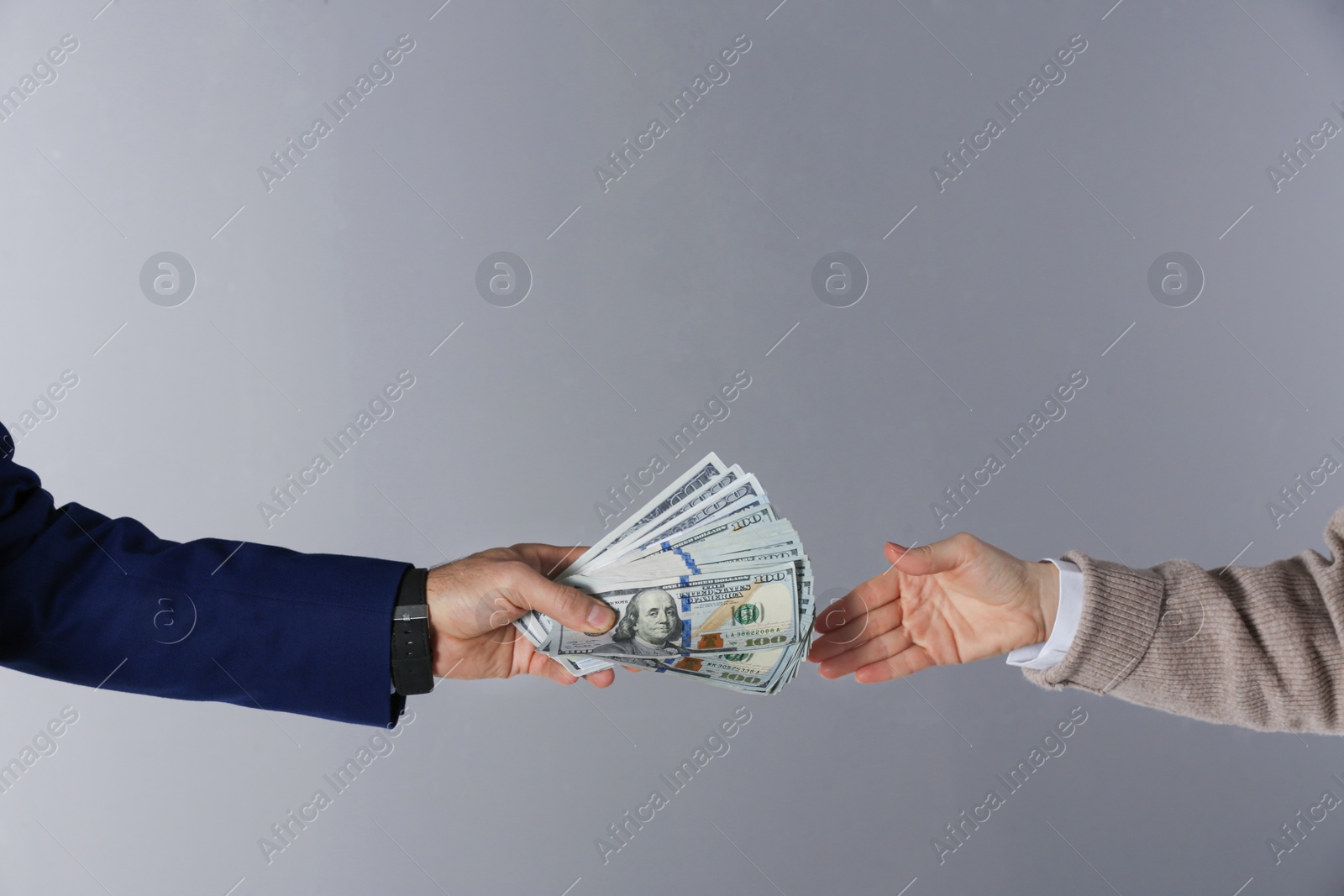 Photo of Man giving bribe money to woman on grey background, closeup