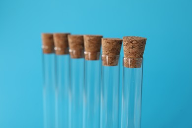 Photo of Test tubes on light blue background, closeup. Laboratory glassware