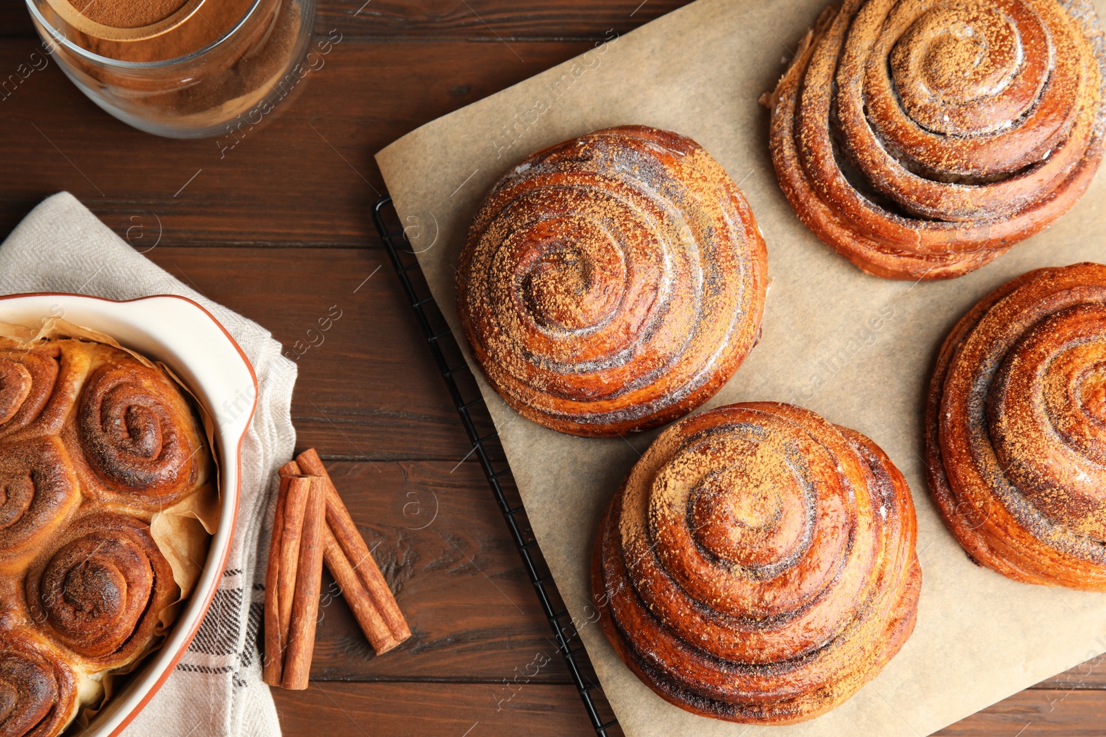 Photo of Flat lay composition with freshly baked cinnamon rolls on wooden background