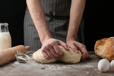 Male baker preparing bread dough at kitchen table, closeup