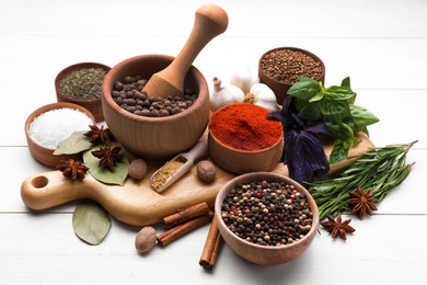 Mortar with pestle and different spices on white wooden table