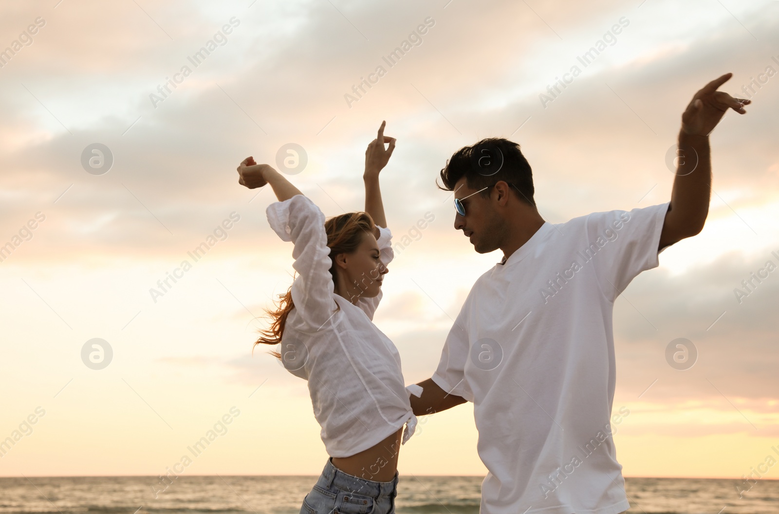 Photo of Happy couple dancing on beach at sunset