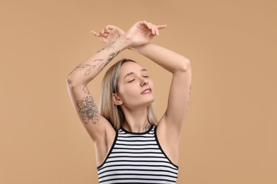 Portrait of beautiful tattooed woman on beige background