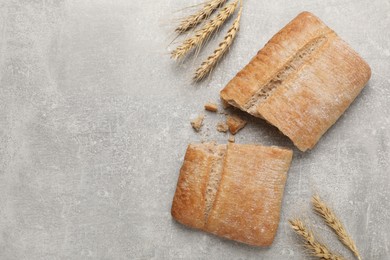 Photo of Fresh crispy ciabatta and spikelets on grey table, flat lay. Space for text