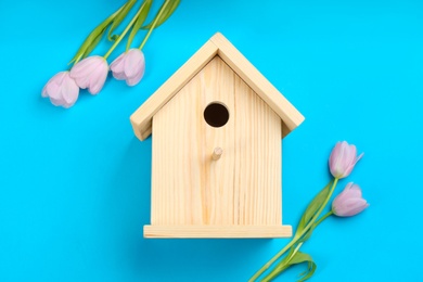 Beautiful bird house and pink tulips on light blue background, flat lay
