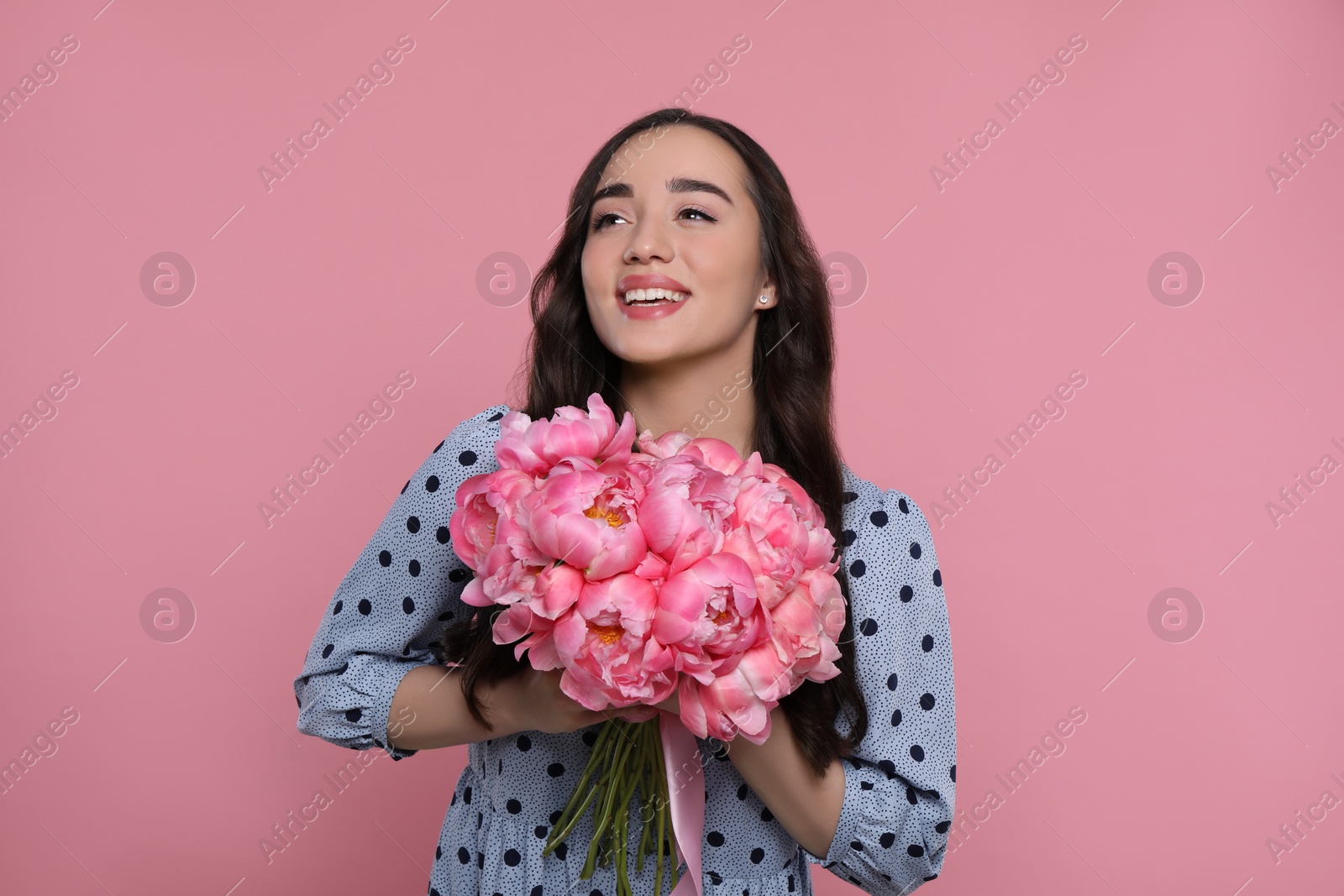 Photo of Beautiful young woman with bouquet of peonies on pink background