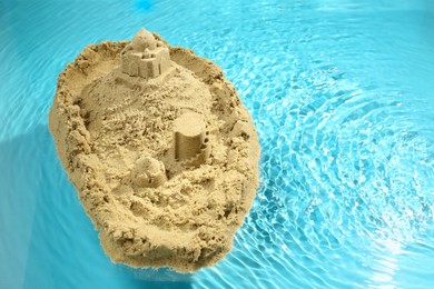Photo of Pile of sand with beautiful castle on rippled water. Space for text