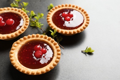 Photo of Tasty tartlets with jam on grey background