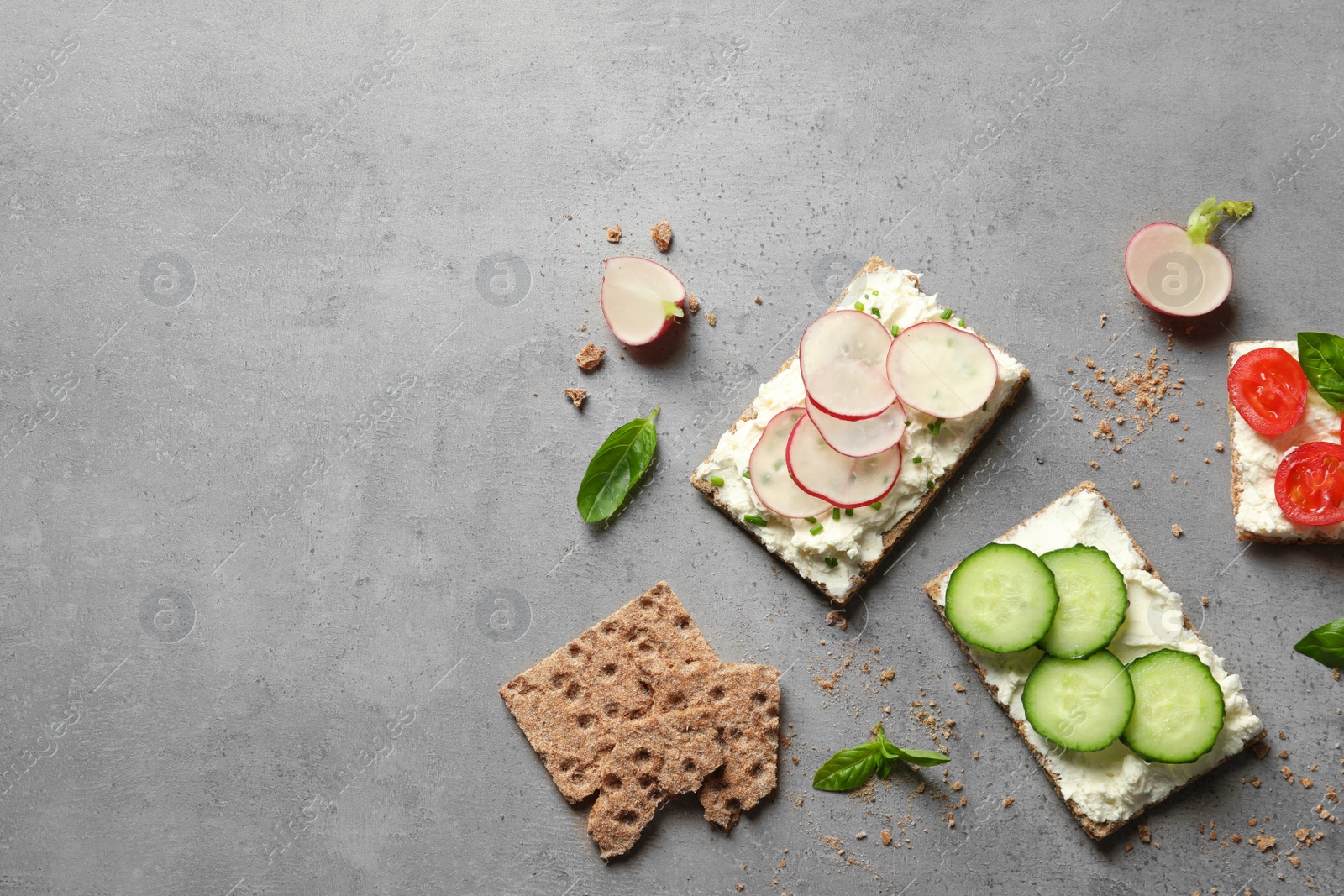 Photo of Tasty snacks with cream cheese and vegetables on gray table, flat lay. Space for text