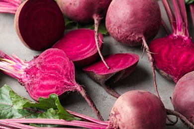 Cut and whole raw beets on light grey table