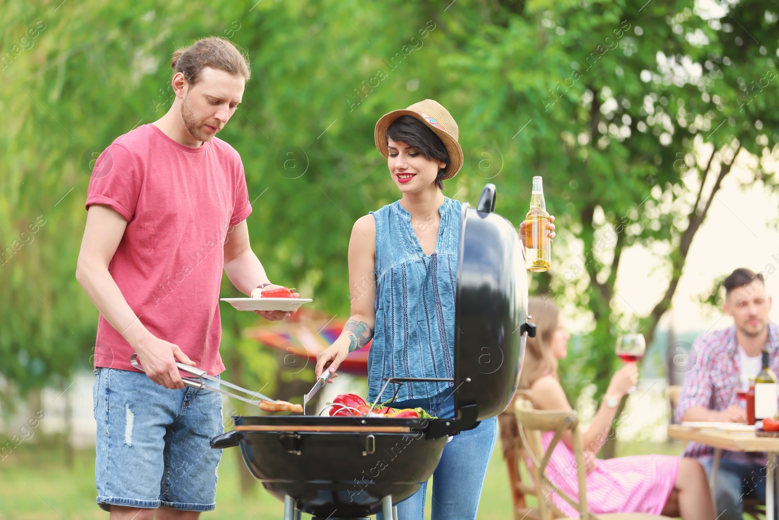 Photo of Young people having barbecue with modern grill outdoors