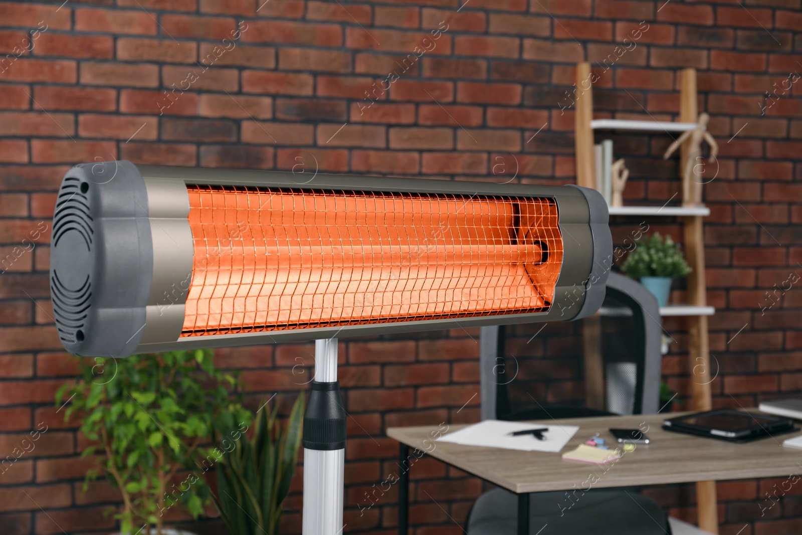 Photo of Electric infrared heater near brick wall in stylish room, closeup
