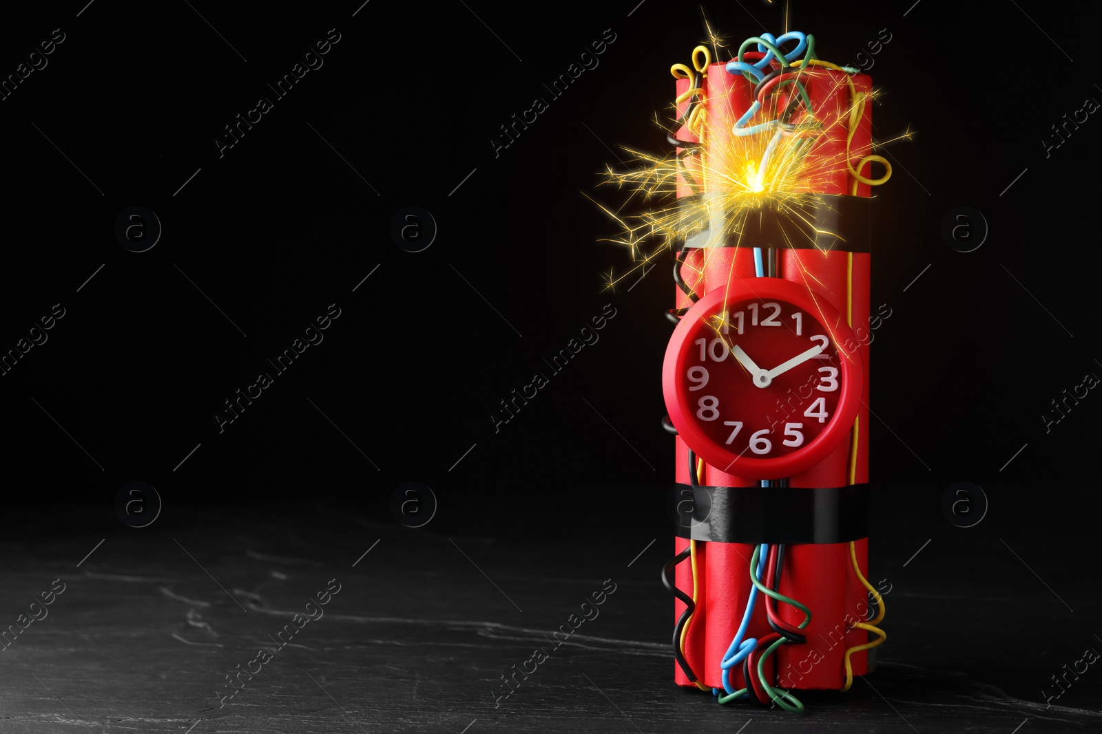 Image of Dynamite time bomb with burning wires on black table, space for text