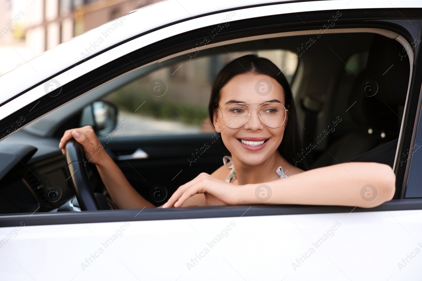 Photo of Enjoying trip. Happy young woman in car, view from outside