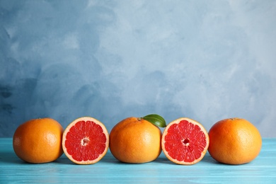 Photo of Fresh tasty grapefruits on table against color background. Space for text