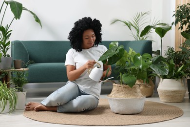 Photo of Woman watering beautiful monstera with water at home. Houseplant care