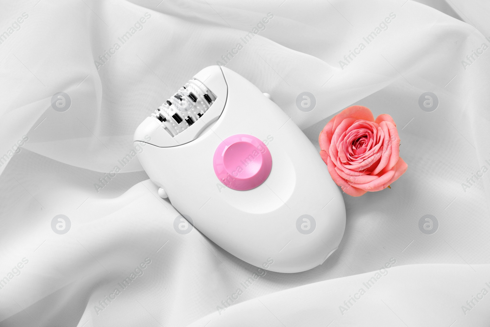 Photo of Modern epilator and flower on light fabric