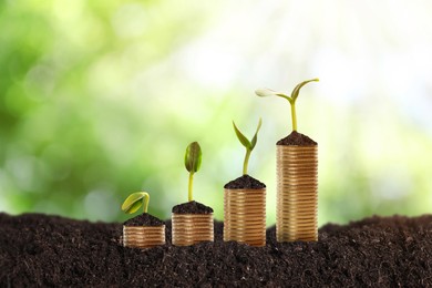 Image of Stacked coins and green seedlings on ground outdoors, bokeh effect. Investment concept