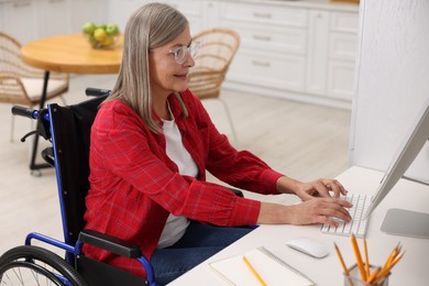 Photo of Woman in wheelchair using computer at table in home office