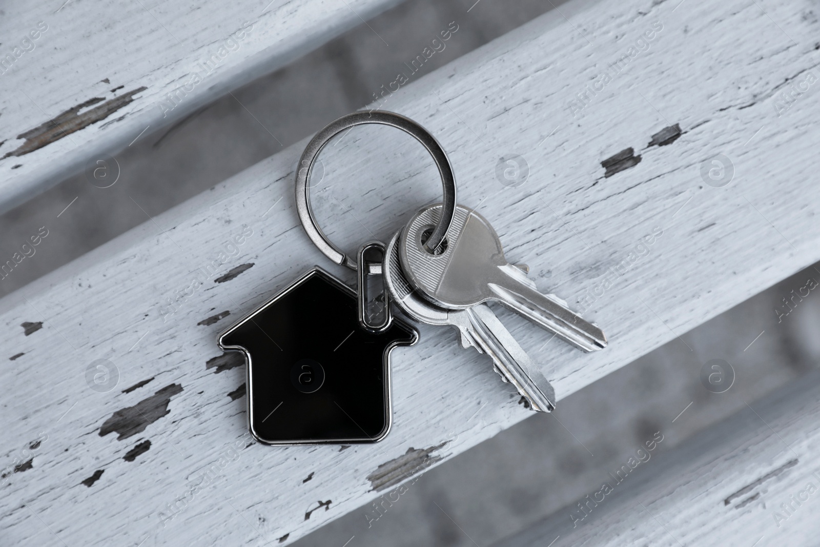 Photo of Keys with trinket in shape of house on wooden surface, top view. Real estate agent services